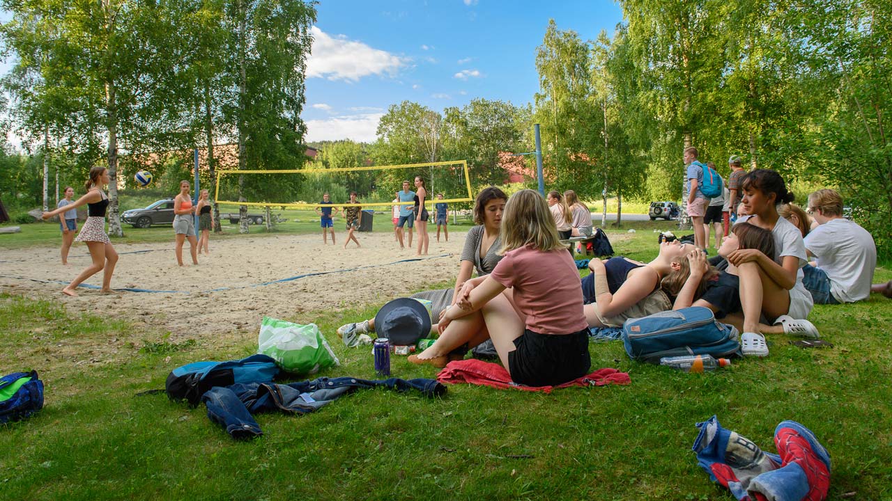 Ungdommer ved volleyballbanen i Kråkvika, sitter på gresset