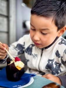 Gutt som spiser cup cake med bringebær