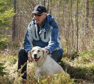 Odd Kåre Olsby, leder av eldrerådet, sitter i skogen med hunden Mira (en golden retriver).